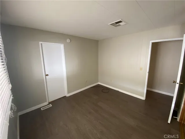 an empty room with wooden floor and mirror