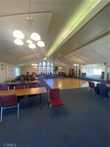 a living room with couches a fireplace and a dining table with wooden floor