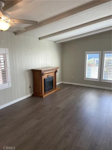 an empty room with wooden floor fireplace and windows