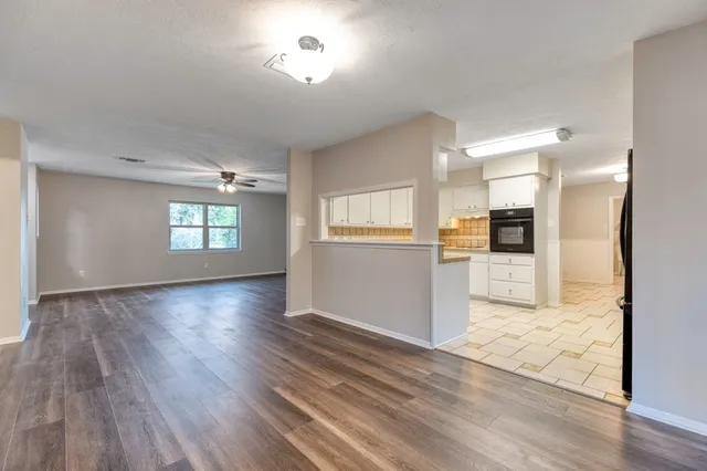 an empty room with wooden floor and a kitchen
