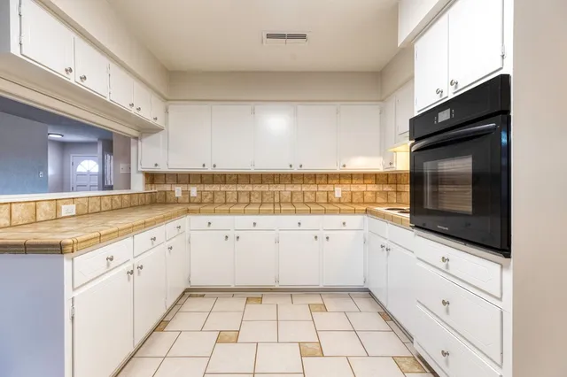 a kitchen with granite countertop white cabinets a sink dishwasher and a stove with wooden floor