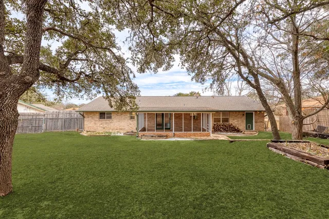 a view of a house with a big yard and large trees