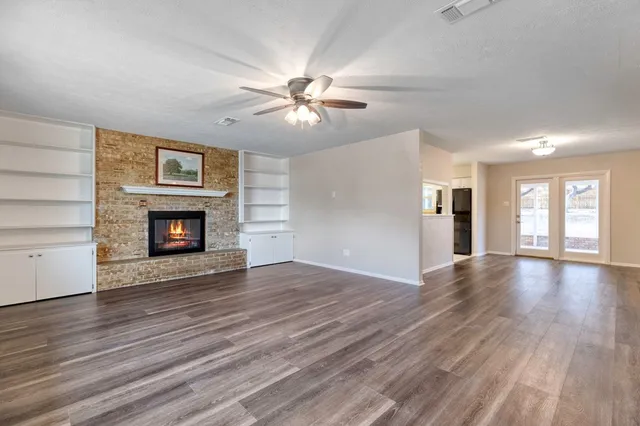a view of an empty room with wooden floor fireplace and a window