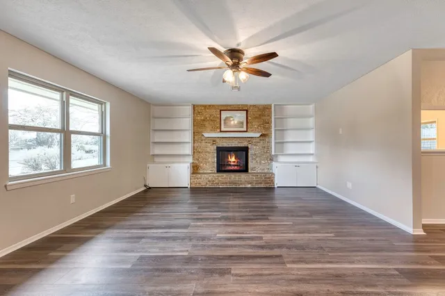 a view of an empty room with a window and fireplace