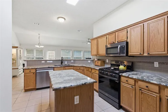 a kitchen with stainless steel appliances granite countertop a stove top oven a sink dishwasher and a microwave oven on the blue kitchen countertops