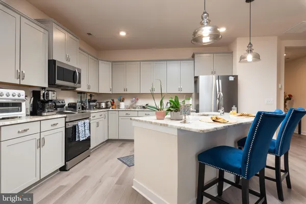 a kitchen with stainless steel appliances a table chairs refrigerator and microwave