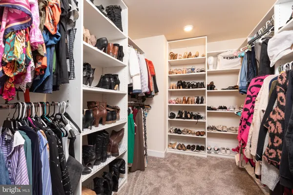 a view of walk in closet with clothes and shoes