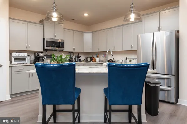 a kitchen with stainless steel appliances a refrigerator a stove a sink dishwasher a dining table and chairs