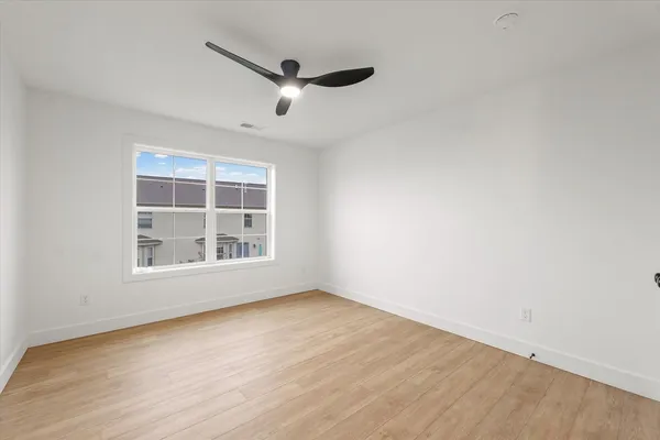 an empty room with wooden floor cabinet and windows