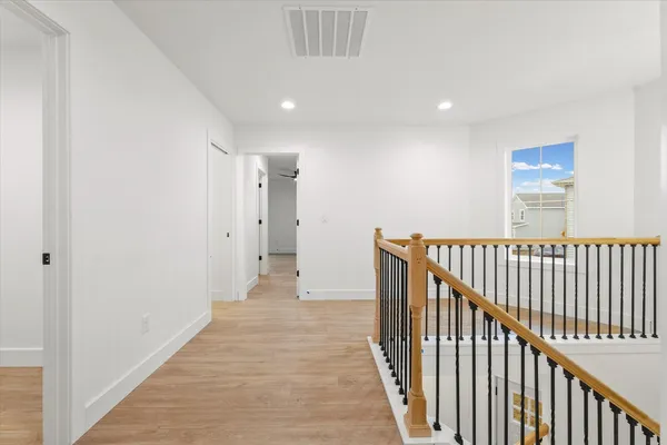 a view of a hallway with wooden floor and a bathroom