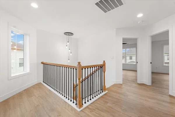 a view of a hallway with wooden floor and windows