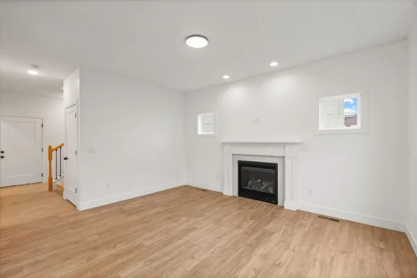 a view of empty room with wooden floor and fireplace