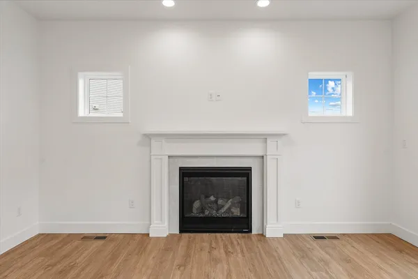 a view of an empty room with wooden floor and a fireplace