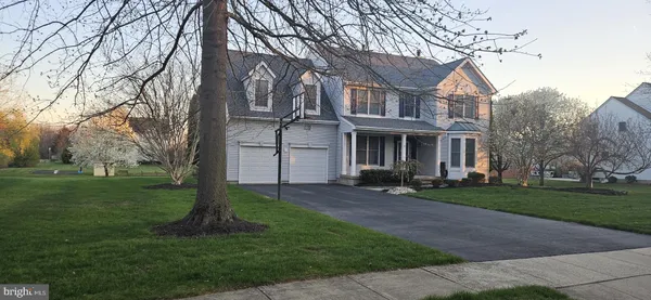 a view of a big yard in front of a brick house with large windows
