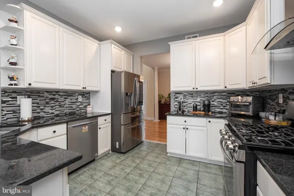 a kitchen with stainless steel appliances granite countertop a stove refrigerator sink and cabinets