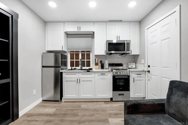 a kitchen with stainless steel appliances granite countertop a stove top oven a sink and a refrigerator