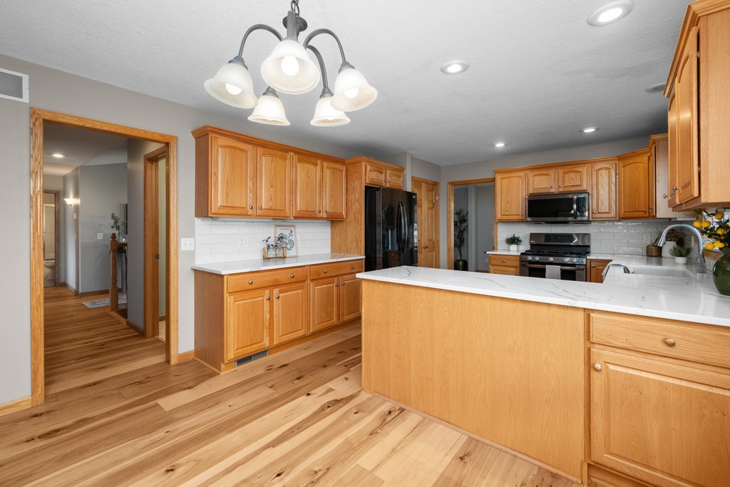 1126 West Le Claire Road Eldridge, IA 52748 - Photo 25 of 44 a large kitchen with stainless steel appliances granite countertop a stove a sink dishwasher a microwave oven with cabinets and wooden floor