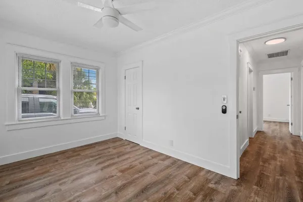 a view of a house in front of a yard with plants and large trees