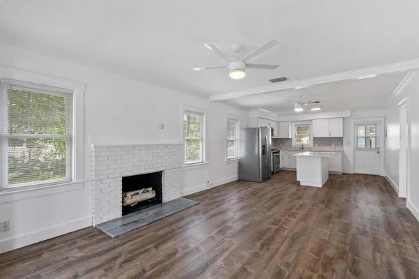 a view of a big room with wooden floor fireplace and windows