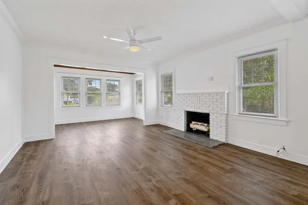 a view of a livingroom with wooden floor a fireplace and window