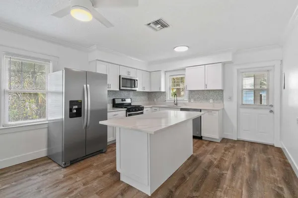 a kitchen with a refrigerator a sink dishwasher and a stove with wooden floor