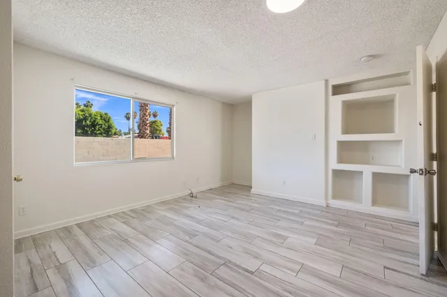 a view of empty room with wooden floor and window