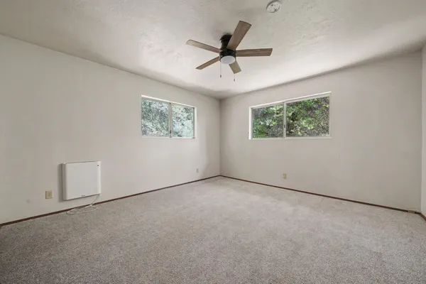 an empty room with window and ceiling fan