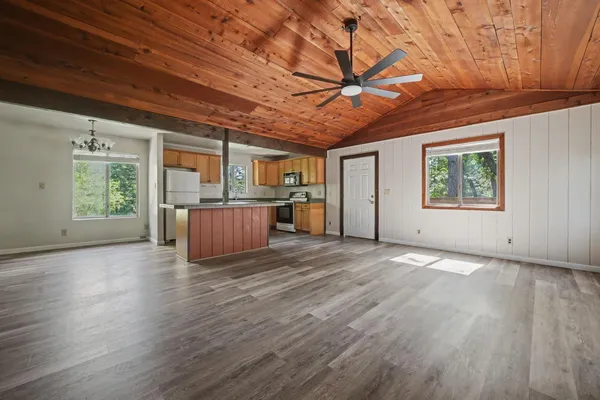 a view of empty room with wooden floor and fan