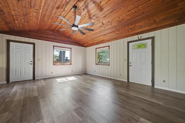 a view of an empty room with wooden floor and a window