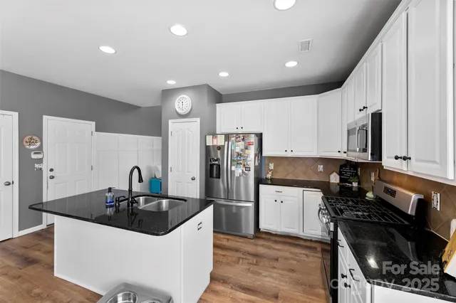a kitchen with stainless steel appliances a sink a stove a microwave and cabinets