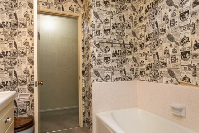 an empty room with chandelier fan and windows