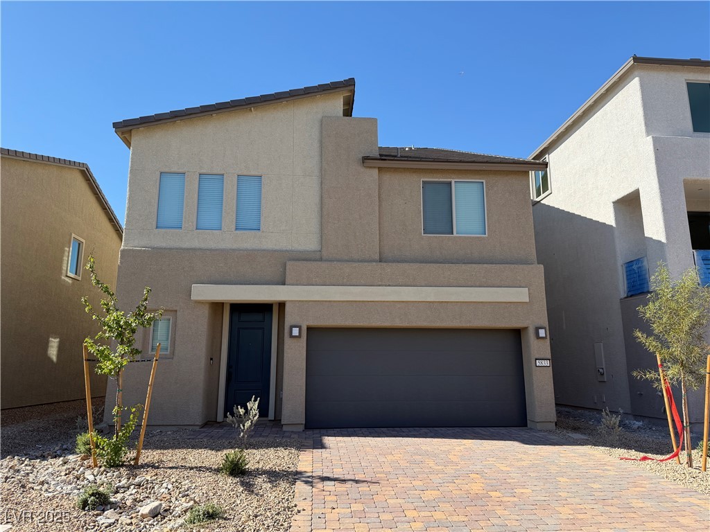 View of front of property with stucco siding, a garage, and decorative driveway