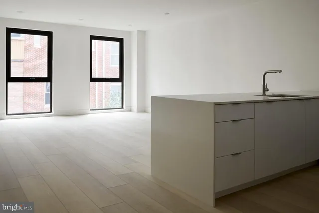 a large white kitchen with a sink stainless steel appliances and cabinets