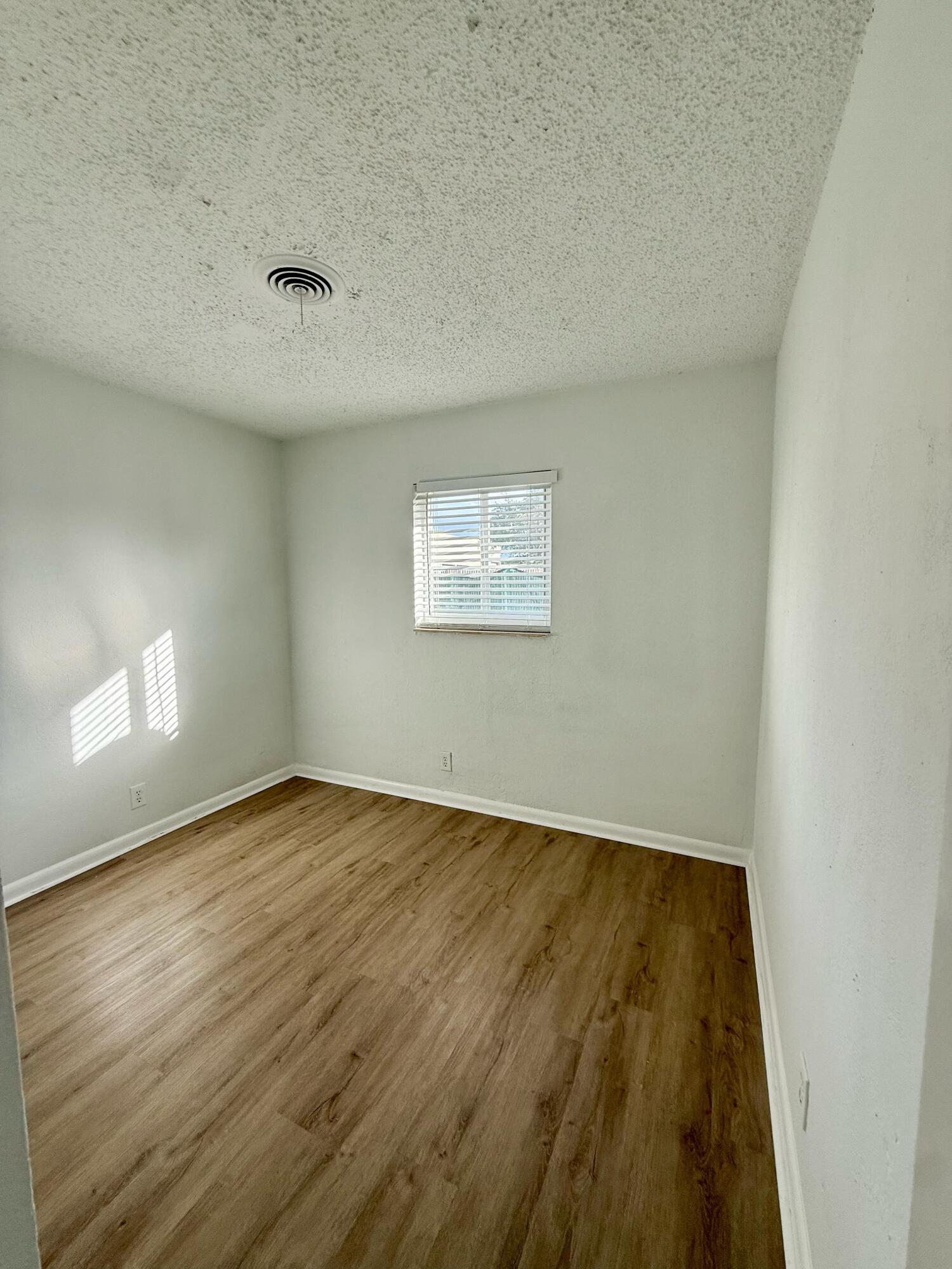 2925 Northeast 7th Avenue, Unit A Pompano Beach, FL 33064 - Photo 7 of 14 an empty room with wooden floor and windows