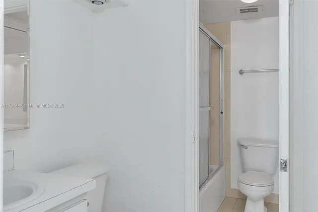 a bathroom with a granite countertop toilet and a sink