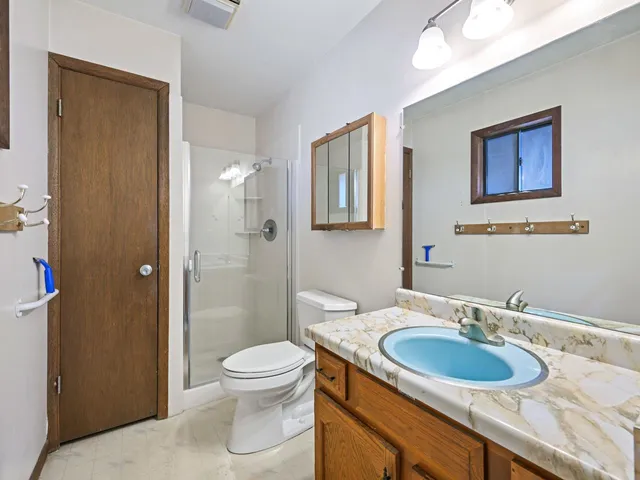 a bathroom with a granite countertop sink toilet a mirror and shower