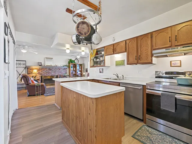 a kitchen with stainless steel appliances granite countertop a sink a stove and a wooden floors