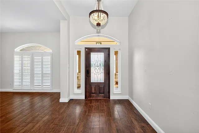 an empty room with wooden floor a window and a chandelier