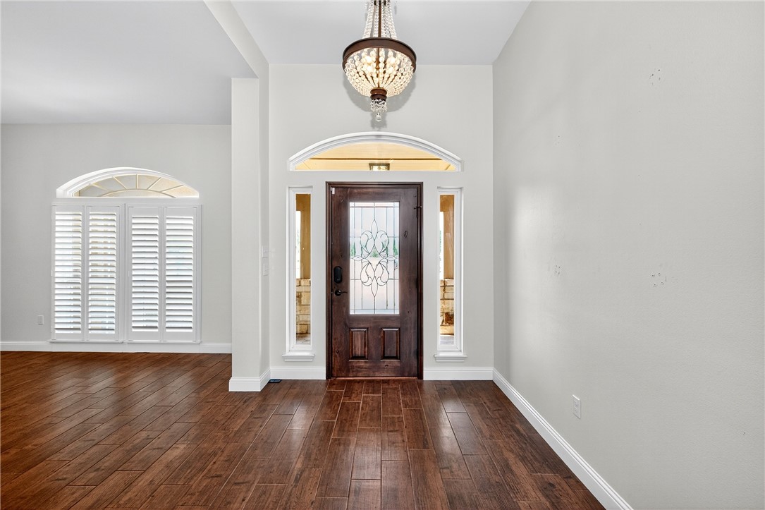 5332 Alegre Lane Robstown, TX 78380 - Photo 13 of 40 an empty room with wooden floor a window and a chandelier