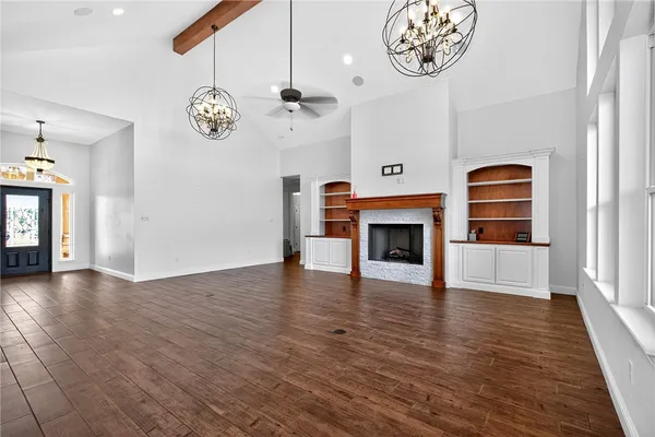 an empty space with a fireplace a ceiling fan and wooden floor
