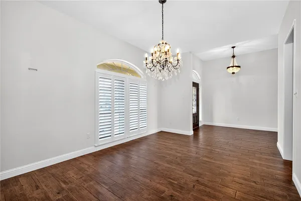 a view of an empty room with wooden floor and a chandelier