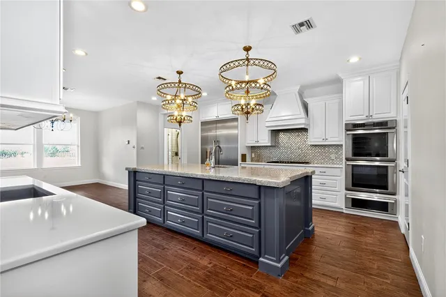 a large kitchen with stainless steel appliances granite countertop a stove and a wooden floors