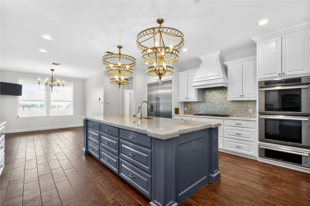 a kitchen with kitchen island granite countertop a sink stainless steel appliances and cabinets