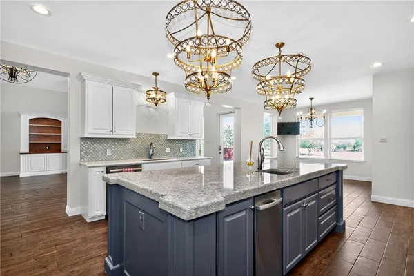 a kitchen with stainless steel appliances granite countertop a sink dishwasher a stove a dining table and chairs with wooden floor