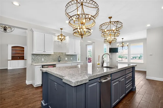 a kitchen with stainless steel appliances granite countertop a sink dishwasher a stove a dining table and chairs with wooden floor