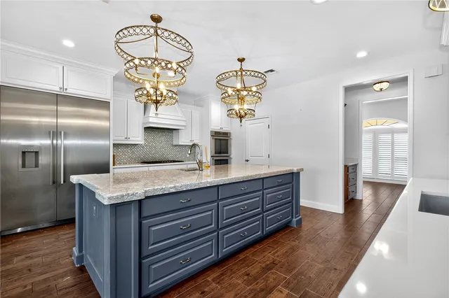 a kitchen with stainless steel appliances granite countertop a sink a refrigerator and wooden floor