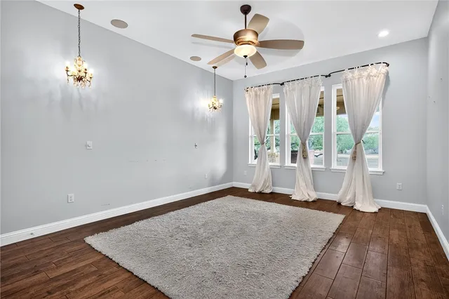 a view of an empty room and wooden floor and a ceiling fan