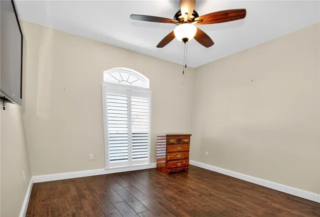 an empty room with wooden floor chandelier fan and windows