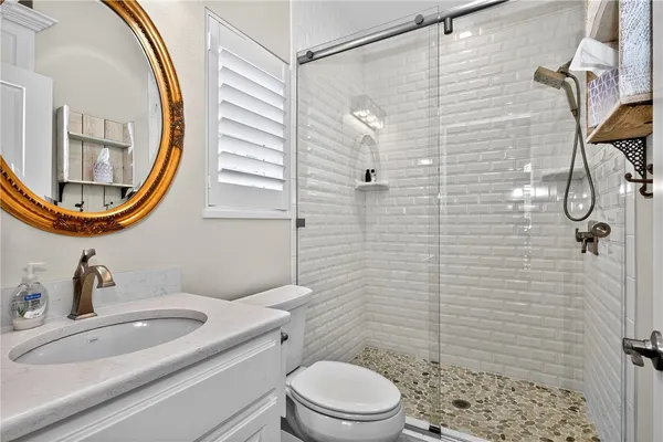 a bathroom with a sink a mirror a toilet and shower