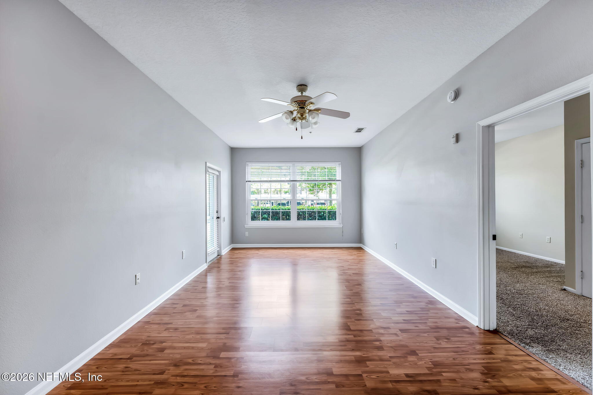 7990 Baymeadows Road East, Unit 520 Jacksonville, FL 32256 - Photo 12 of 41 an empty room with wooden floor chandelier fan and windows